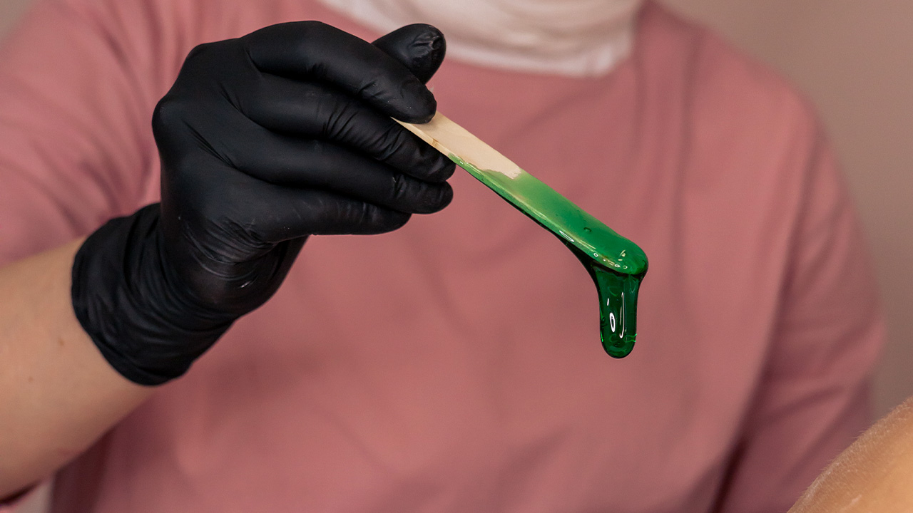 Profissional aplicando cera de forma suave durante o atendimento especializado de depilação em Vinhedo na clínica Lumière Concept.